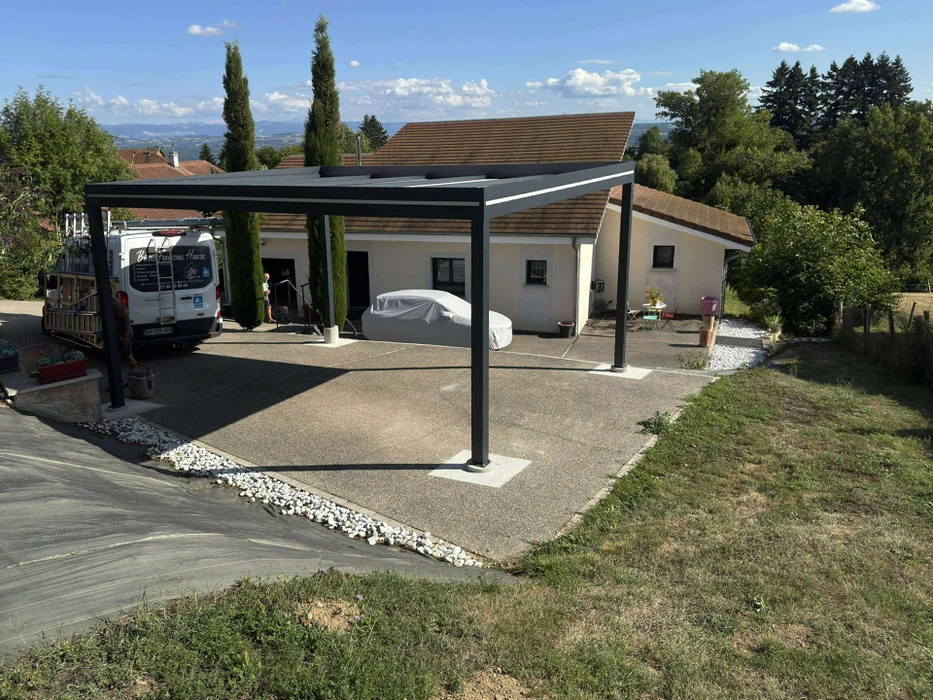 Chantier extérieur résidentiel avec ouvrier installant un carport moderne à structure métallique noire et toiture plate