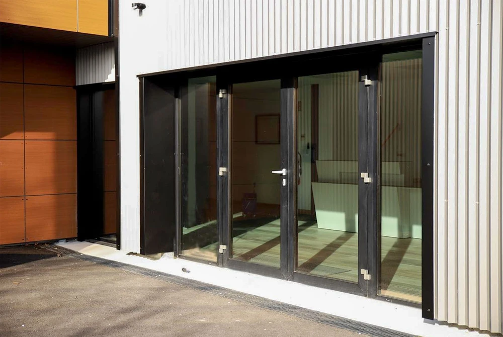 Extérieur d'un bâtiment moderne avec façade métallique blanche nervurée et section en bois