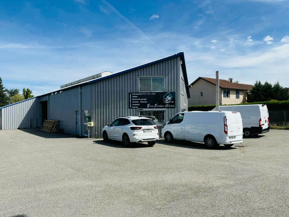 Ouvrier d'usine assemblant un cadre de fen&ecirc;tre en pvc blanc &agrave; l'aide d'un tournevis pneumatique dans une grande salle de production