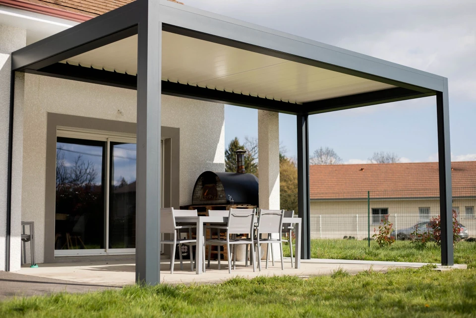 Extension moderne d'habitation avec structure m&eacute;tallique grise et large baie vitr&eacute;e &agrave; cadres bleus fonc&eacute;s